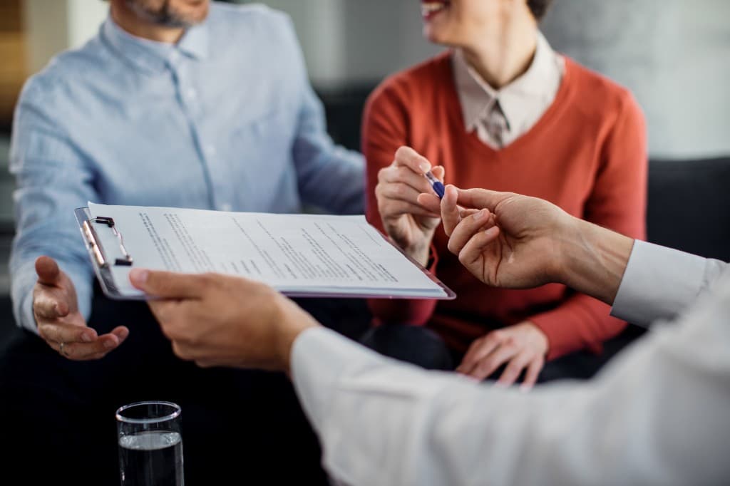 Pareja firmando un contrato con su asesor de seguros